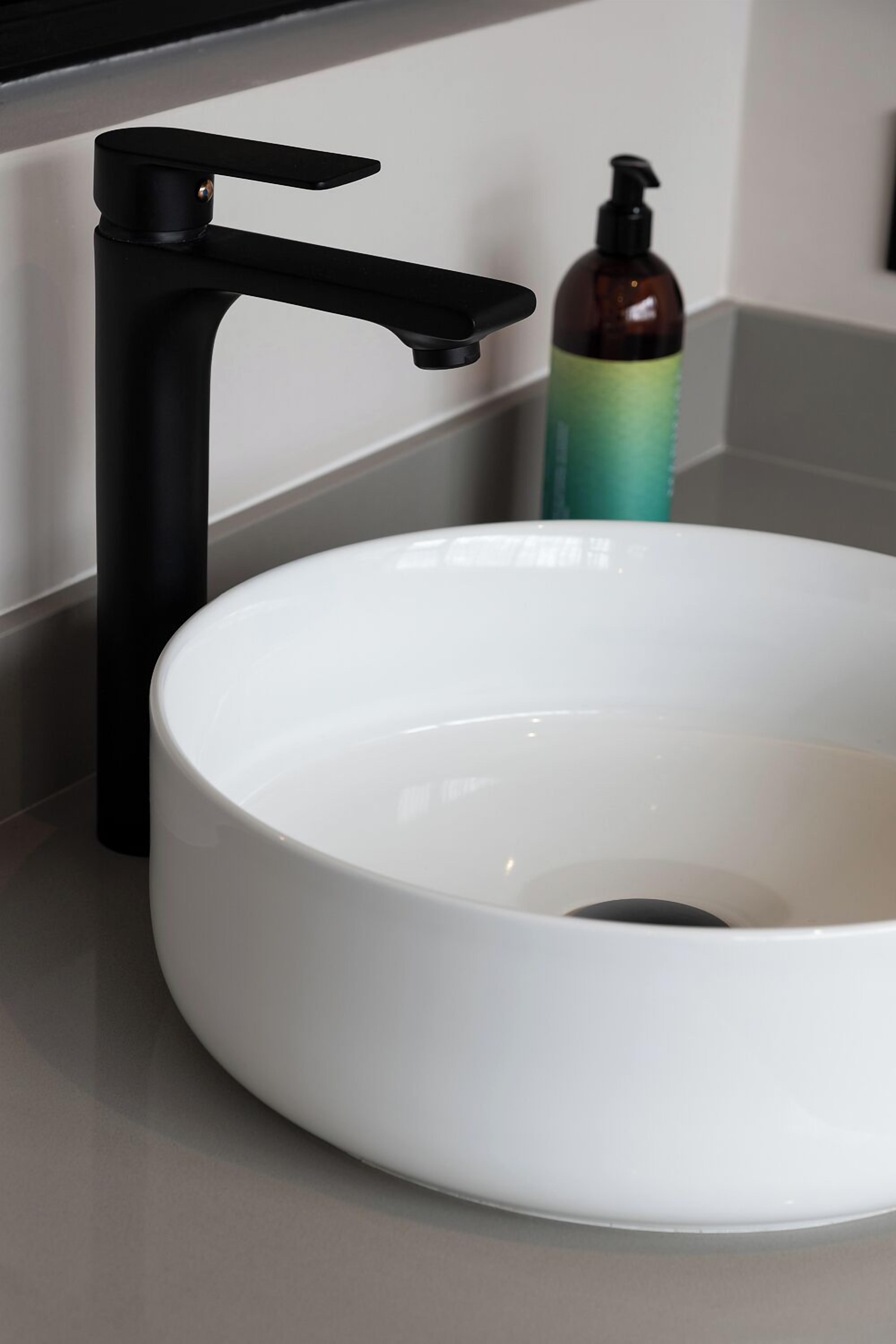 A white sink with a black faucet on a countertop.