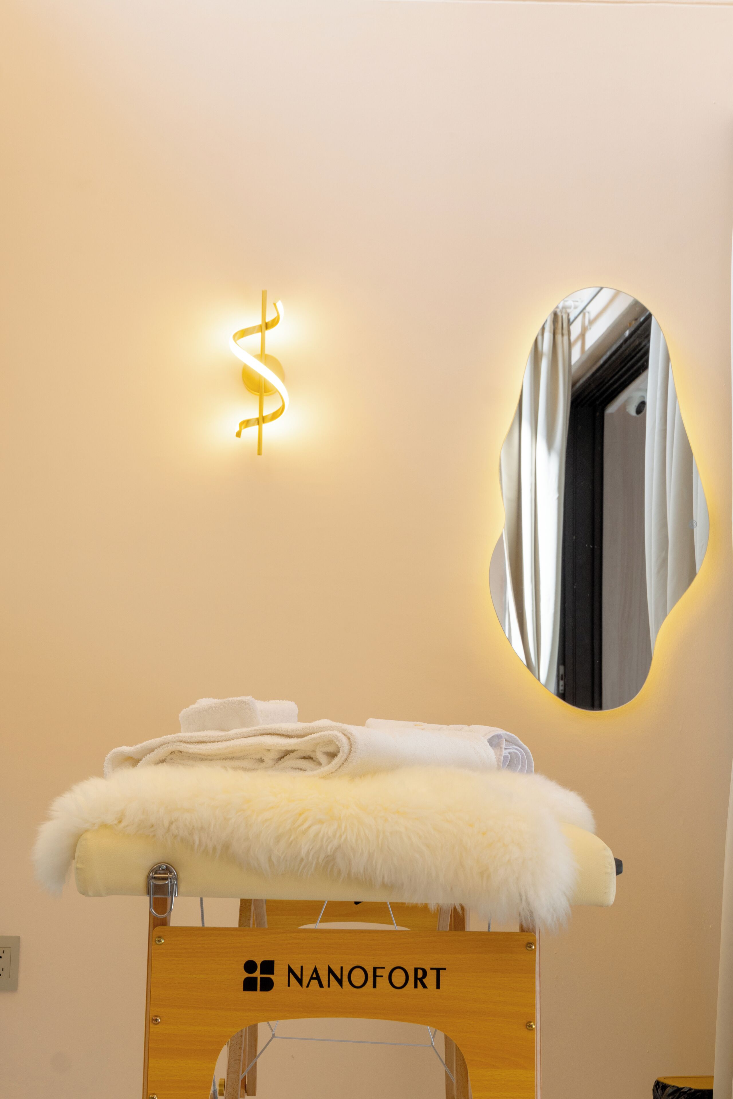 A neatly arranged bathroom with a towel rack, a mirror, and a wall-mounted light fixture.