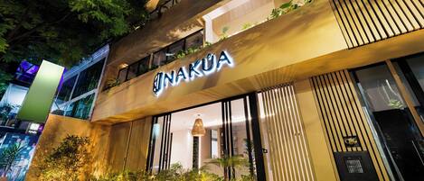 A modern building with a sign reading "NAKUA" and a well-lit entrance.