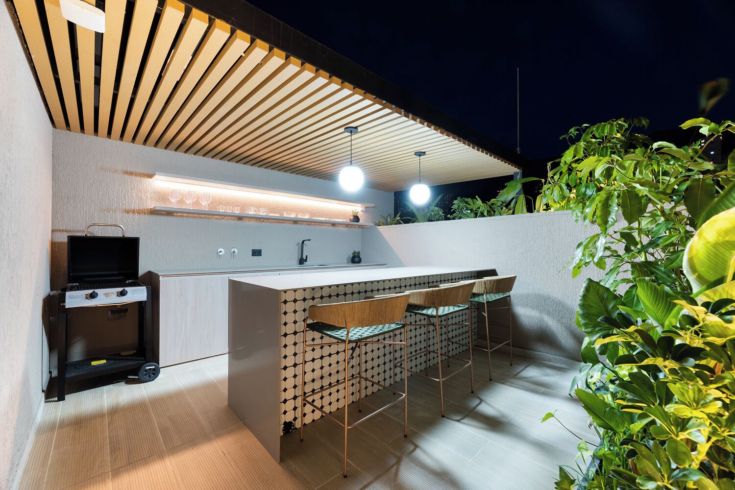 An outdoor kitchen area with a grill, bar counter, and seating.