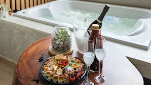 A room with a wooden table, a hot tub, and a scenic view of trees and mountains. - Nakúa Stay + Work (Medellín)