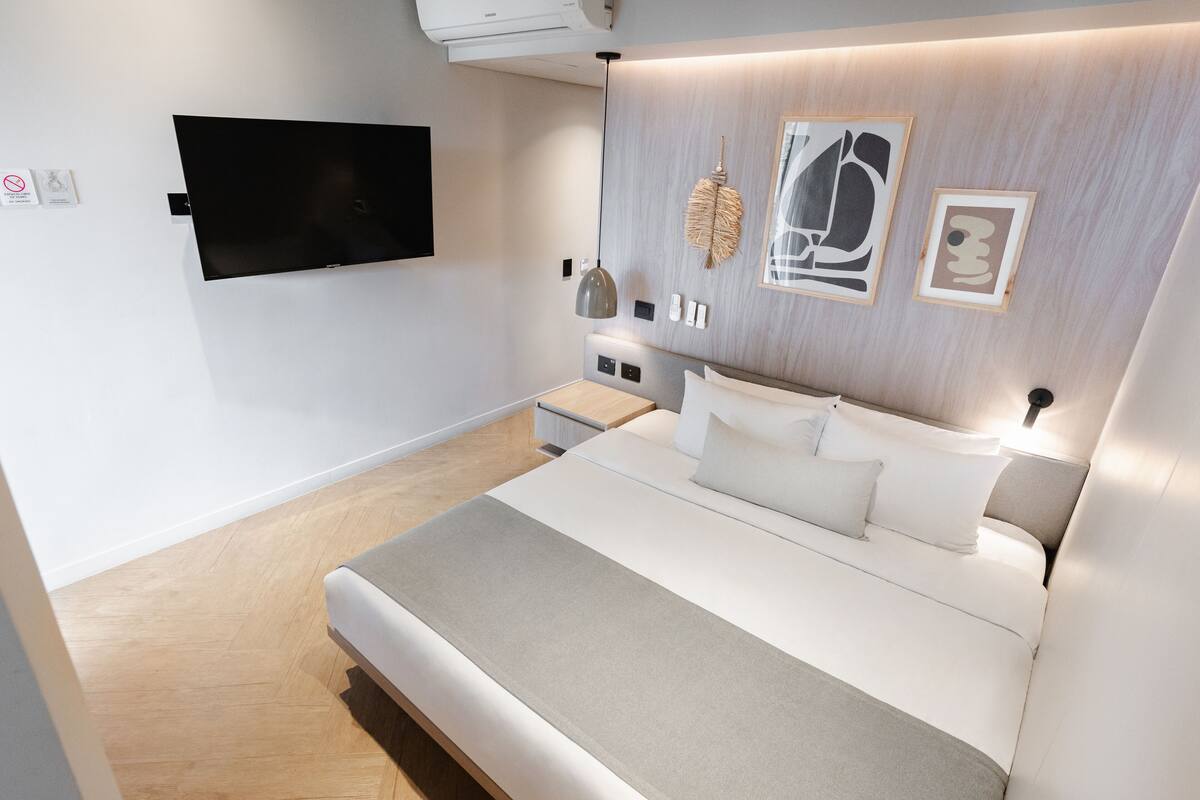 Ein modernes Schlafzimmer mit einem großen Bett, einem an der Wand montierten Fernseher und Kunstwerken.
