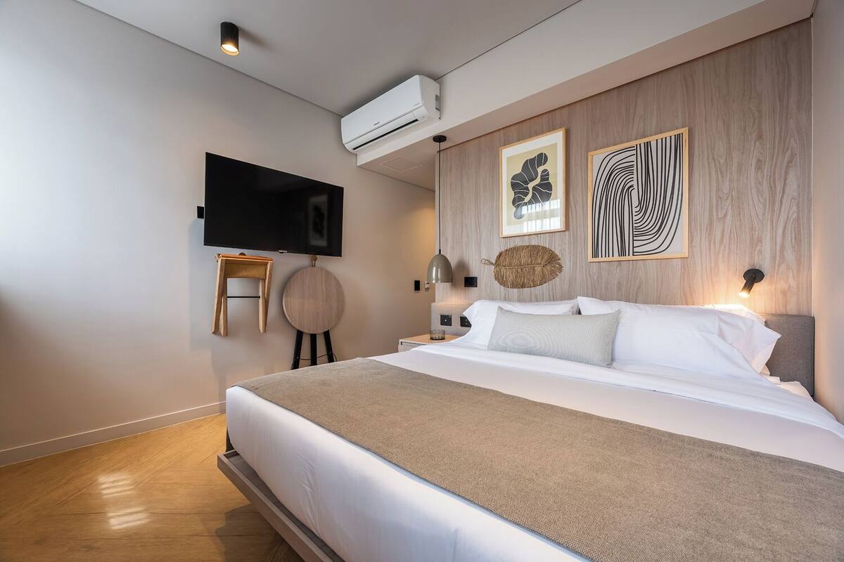 Ein modernes Hotelzimmer mit einem großen Bett, einem an der Wand befestigten Fernseher und Kunstwerken an der Wand.