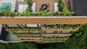 A modern rooftop terrace with a wooden slatted roof, multiple planters with greenery, a small round table, and a seating area with chairs. - Nakúa Stay + Work (Medellín)