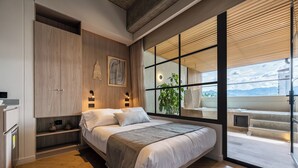 A modern bedroom with a large bed, built-in wardrobe, bedside lamps, and a view of a balcony. - Nakúa Stay + Work (Medellín)