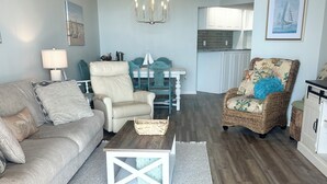 A living room with a sofa, armchairs, a coffee table, and a dining table.