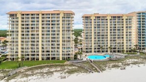 A high-rise hotel with multiple balconies, a central pool, and a beachside location.