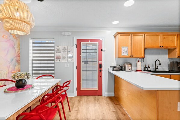 Une cuisine moderne avec des meubles en bois, un plan de travail blanc et une porte rouge.
