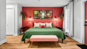 Une chambre à coucher comprenant un lit, des tables de chevet, un banc, un ventilateur de plafond et des lampes fixées au mur.