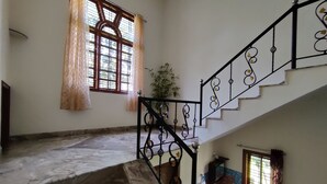 Una escalera con barandilla de metal y una ventana con cortinas estampadas.