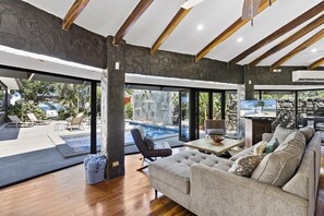 A modern living room with a pool, large windows, and a television.