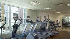 A gym with treadmills, ellipticals, and stationary bikes arranged in rows. - Las Vegas | Vegas Weekend Escape | Pool & Resort | 2BR (Las Vegas)