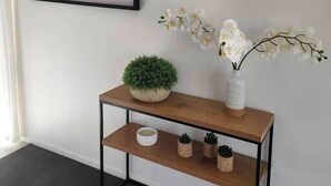 Una stanza moderna con un elegante tavolino consolle, un quadro astratto incorniciato e un vaso con orchidee bianche.