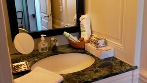 Et badeværelse med en hvid vask, et spejl, et håndklæde og toiletartikler på bordet.