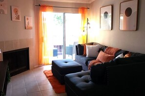 A living room with a sofa, ottoman, fireplace, and artwork on the walls.