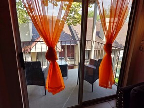 A balcony with orange curtains, outdoor furniture, and a view of neighboring houses. - A Private Retreat Made for Extended Houston Stays (Houston)