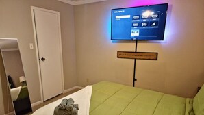 A hotel room with a bed, a television mounted on the wall, and a sign with a motivational message. - A Private Retreat Made for Extended Houston Stays (Houston)