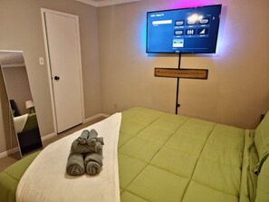 A hotel room with a bed, a television mounted on the wall, and a sign with a motivational message. - A Private Retreat Made for Extended Houston Stays (Houston)