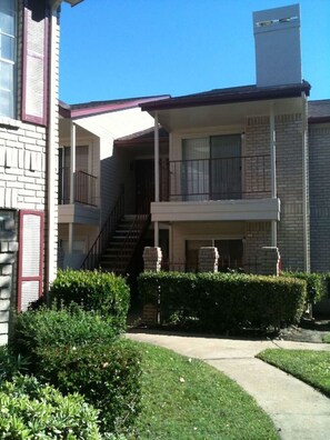 A two-story building with a balcony on the ground floor and a staircase leading to the upper floor. - A Private Retreat Made for Extended Houston Stays (Houston)