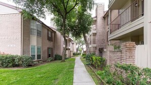 A residential building with brick exteriors, a central pathway, and surrounding greenery. - A Private Retreat Made for Extended Houston Stays (Houston)
