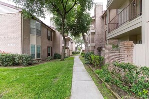 A residential building with brick exteriors, a central pathway, and surrounding greenery. - A Private Retreat Made for Extended Houston Stays (Houston)