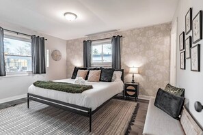 A bedroom with a bed, bedside tables, a lamp, and a view of the outdoors. - OliveBranch-LuxeDesigner Home-Spa-Firepit-GameZone (Greenwood)