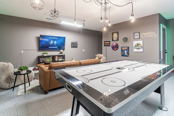 A room with a foosball table, a TV, and various posters on the wall. - OliveBranch-LuxeDesigner Home-Spa-Firepit-GameZone (Greenwood)