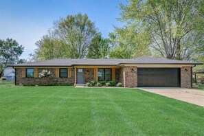 A single-story house with a brick facade, a front garage, and a well-maintained lawn. - OliveBranch-LuxeDesigner Home-Spa-Firepit-GameZone (Greenwood)