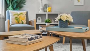 A modern living room with a sofa, a coffee table, and a bookshelf. - Zestlife-HeatedPool-LuxeEscp-ThemedRooms-GameRoom (Indianapolis)