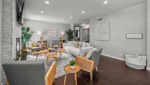 A modern living room with a grey sofa, wooden coffee table, and a fireplace. - Zestlife-HeatedPool-LuxeEscp-ThemedRooms-GameRoom (Indianapolis)