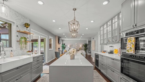 A modern kitchen with a central island, stainless steel appliances, and a farmhouse sink. - Zestlife-HeatedPool-LuxeEscp-ThemedRooms-GameRoom (Indianapolis)