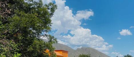 A pool area with a clear blue pool, stone walls, and a mountain in the background.