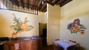 A kitchen with a wooden counter, a sink, and a dining table with chairs. There is a mural on the wall depicting fruits and vegetables. - Hotel Quinta Sta Cecilia (Cuatro Ciénegas)