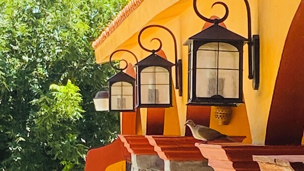 A building with a yellow facade, black wrought iron lanterns, and a stone balustrade. - Hotel Quinta Sta Cecilia (Cuatro Ciénegas)