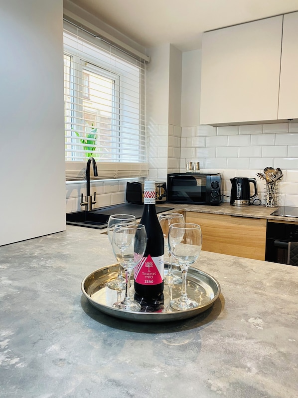 Enjoy cooking in this well-equipped kitchen with a stainless steel countertop, black coffee machine, and wine glasses.
