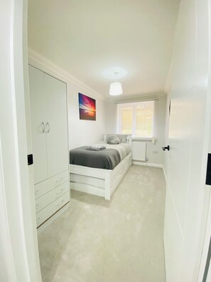 Cozy retreat with a single bed, wardrobe, and window with blinds.