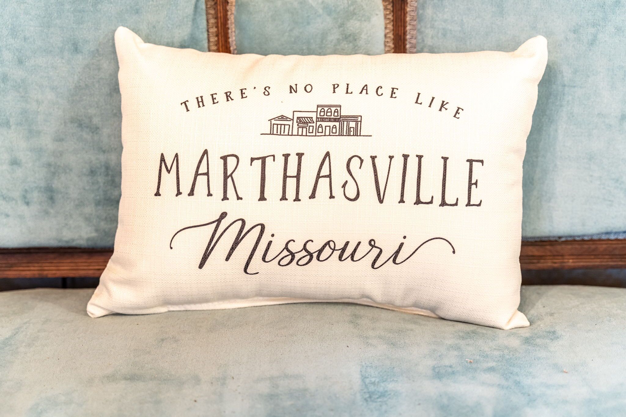 Een kussen met de tekst 'There's no place like MARTHASVILLE, Missouri' en een kleine tekening van een gebouw.