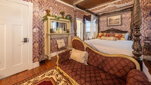 A bedroom with a large bed, ornate furniture, and patterned wallpaper. - TheOutPostInn Bed&Breakfast - The Purple Victorian (Marthasville)