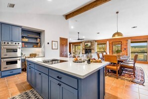 A kitchen with a central island, built-in ovens, and a dining area with a view. - The Lodge II | Lake Views, Hot Tub & Hill Country (Ingram)