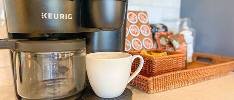 A Keurig coffee maker with a glass carafe and a white mug on a kitchen counter.