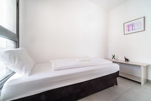 Une chambre à coucher au style minimaliste, avec un lit, une fenêtre, une étagère fixée au mur ornée d’une plante et un tableau encadré.