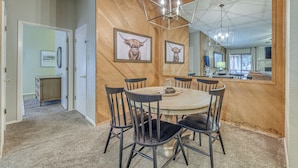 A dining area with a round table, six chairs, a chandelier, and two framed animal pictures on the wall. - 1 Mi to Ski Slopes: Alto Escape w/ Game Room! (Alto)