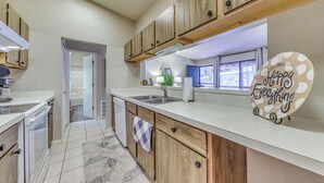 A modern kitchen with wooden cabinets, white countertops, and a view to the outside. - 1 Mi to Ski Slopes: Alto Escape w/ Game Room! (Alto)