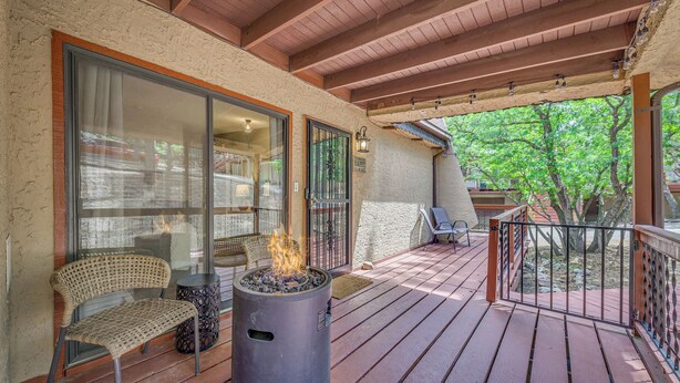 A wooden deck with a fire pit, outdoor seating, and a view of the surrounding trees. - 1 Mi to Ski Slopes: Alto Escape w/ Game Room! (Alto)