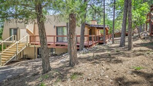 A cabin with a wooden deck, a staircase, and a view of the surrounding forest. - 1 Mi to Ski Slopes: Alto Escape w/ Game Room! (Alto)