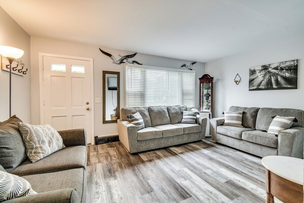A living room with two grey sofas, a coffee table, and a wooden floor.