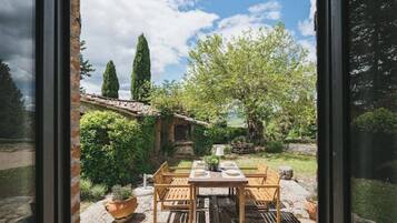 A patio with a table set for four, surrounded by stone flooring and potted plants.