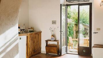 A kitchen with a wooden counter, a small table with a vase, and a sliding glass door leading to an outdoor seating area.