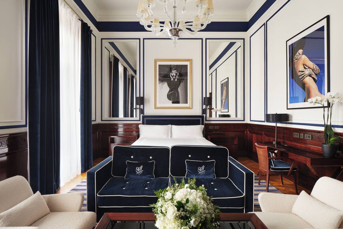A spacious room with a large bed, two sofas, a coffee table, and a chandelier.