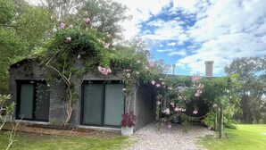 A modern house with a garden path leading to a dark-colored door. - Minutos a Jose Ignacio, La Casita De Infinita, en el campo, cerca la playa! (Faro de José Ignacio)
